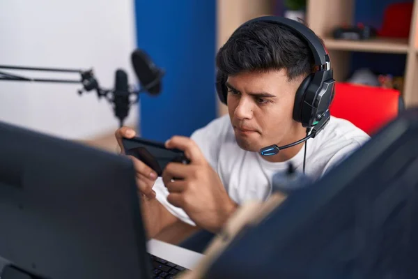 若いヒスパニック系男性ストリーマーゲームルームでスマートフォンを使用してビデオゲームをプレイ — ストック写真