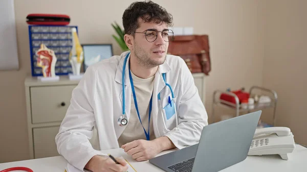 Young Hispanic Man Doctor Using Laptop Working Clinic — Zdjęcie stockowe