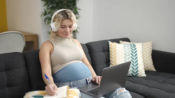 在家里学习使用笔记本电脑和耳机的年轻孕妇 — 图库照片