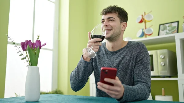 Joven Hispano Bebiendo Copa Vino Usando Smartphone Comedor —  Fotos de Stock