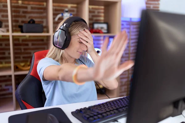 若い白人女性がヘッドフォンをして手で目を覆い 悲しいと恐怖の表現でジェスチャーを停止するビデオゲームをしています 恥をかかせ否定的な概念 — ストック写真