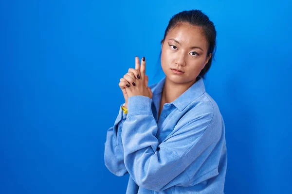 Aziatisch Jong Vrouw Staande Blauwe Achtergrond Met Symbolische Pistool Met — Stockfoto
