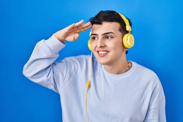 ヘッドフォンを使用して音楽を聴いているノンバイナリの人は 頭の上に手で遠くを見て非常に幸せと笑顔 検索の概念 — ストック写真