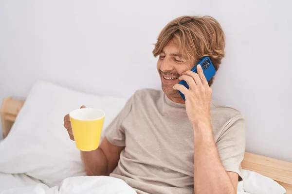 Genç Adam Akıllı Telefonda Konuşuyor Yatak Odasında Kahve Içiyor — Stok fotoğraf