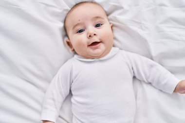 Sevimli bebek yatakta kendinden emin bir şekilde yatıyor.