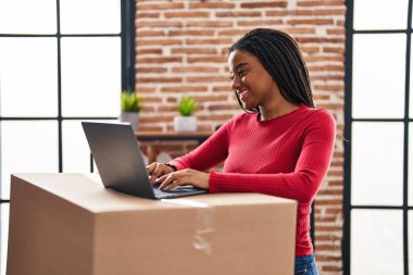 African american woman smiling confident using laptop at new home