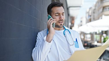 Genç İspanyol doktor hastane raporlarını okuyor. Akıllı telefondan konuşuyor.