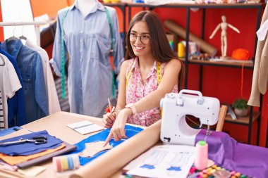 Young beautiful hispanic woman tailor smiling confident speaking at atelier