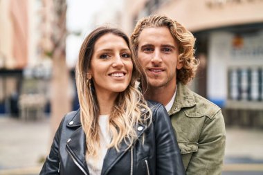 Kadın ve erkek gülümsüyor. Kendilerine güveniyorlar. Sokakta sarılıyorlar.