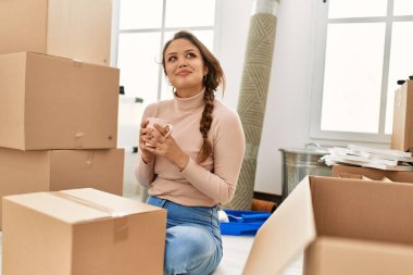 Genç, güzel, İspanyol bir kadın. Yeni evinde yerde oturmuş kahve içiyor.