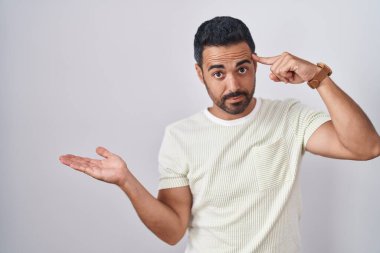 Soyutlanmış arka planda duran İspanyol sakallı bir adam. Avuç içi açık fotokopi alanı ve alnını göstermekten rahatsız ve kafası karışık. Bunu bir düşün.. 