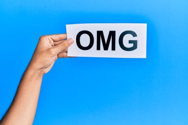 Hand of caucasian man holding paper with omg word over isolated blue background