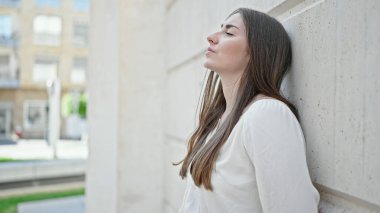 Young beautiful hispanic woman looking to the side with serious expression at street