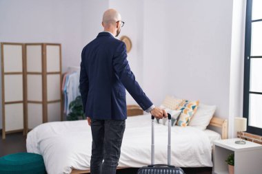 Young hispanic man business worker holding suitcase walking at hotel room
