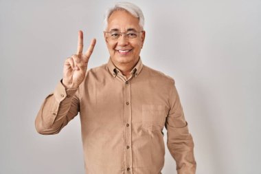 İspanyol kıdemli gözlüklü adam iki numarayı gösterip işaret ederken kendinden emin ve mutlu gülümsüyor.. 