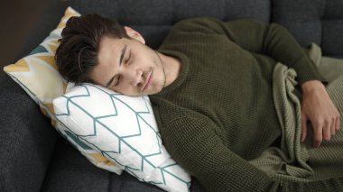 Genç İspanyol adam kanepede uzanıp evde uyuyor.