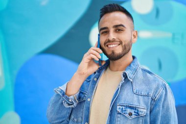 Genç İspanyol adam gülümsüyor. Kendine güveniyor. Sokakta akıllı telefondan konuşuyor.