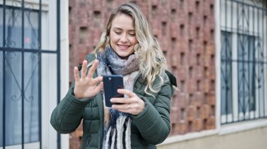Sokakta akıllı telefon kullanan, kendine güvenen genç sarışın kadın.