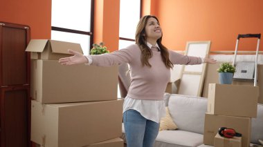 Young beautiful hispanic woman smiling confident standing with arms crossed gesture at new home