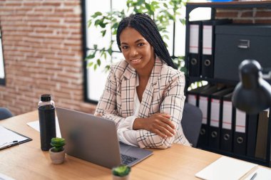Ofiste çalışırken dizüstü bilgisayar kullanan Afrikalı Amerikalı iş kadını.