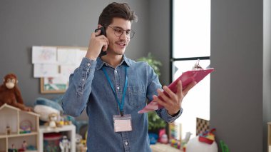 Genç İspanyol anaokulu öğretmeni anaokulunda akıllı telefon okuyarak konuşuyor.