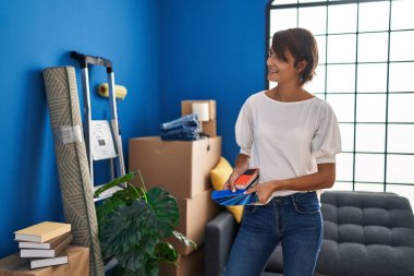 Young beautiful hispanic woman smiling confident holding test color at new home