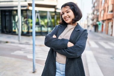 Young woman standing with arms crossed gesture looking to the side at street