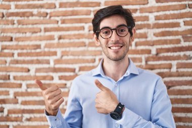 Duvarın arkasında duran İspanyol asıllı genç adam arka tarafı işaret ediyor. Elleri havada, kendinden emin gülümsüyor. 