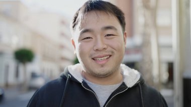 Young chinese man smiling confident standing at street