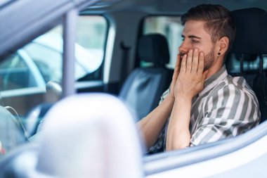Young caucasian man stressed driving car at street