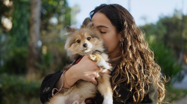 Köpeğiyle parkta öpüşen genç İspanyol kadın.