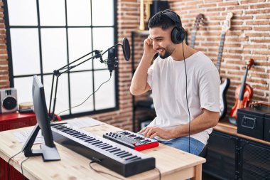 Genç Arap müzisyen müzik stüdyosunda piyano klavyesi çalıyor.