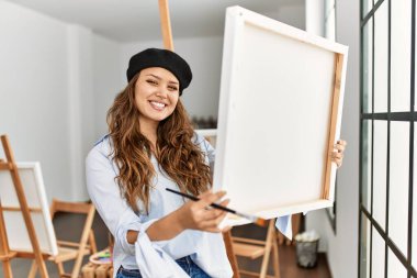 Güzel İspanyol kadın sanatçı gülümsüyor. Sanat stüdyosunda kendine güveni tam görünüyor.