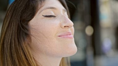 Young blonde woman breathing with closed eyes at street