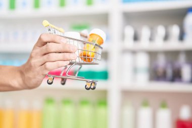 Genç İspanyol eczacı eczanede elinde haplarla market kartı tutuyor.