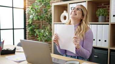 Young beautiful hispanic woman business worker using laptop reading document at office