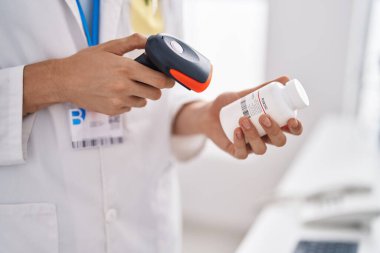 Genç sarışın eczacı eczanede ilaç şişesini tarıyor.