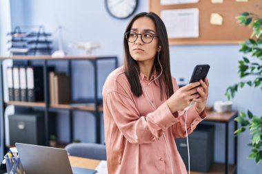 Ofiste akıllı telefon kullanan genç İspanyol iş kadını.