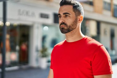 Young hispanic man with relaxed expression standing at street