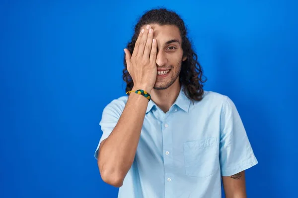 Young Hispanic Man Standing Blue Background Covering One Eye Hand — Stok fotoğraf