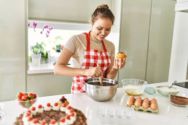 年轻美丽的惊慌失措的女人笑着自信地把巧克力放在厨房的松饼上 — 图库照片