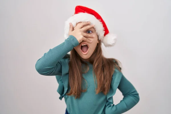 Malá Běloška Vánočním Klobouku Vykukuje Šoku Zakrývá Obličej Oči Rukou — Stock fotografie