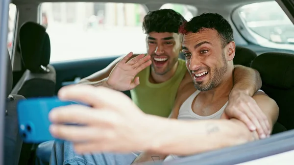二人の男カップルビデオ通話を持っています路上でタクシーに座って — ストック写真