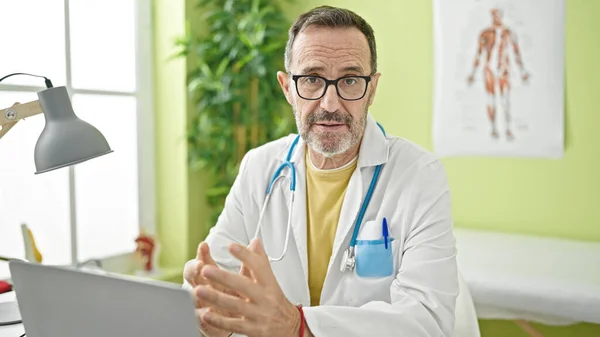 Médico Mediana Edad Usando Portátil Hablando Clínica —  Fotos de Stock