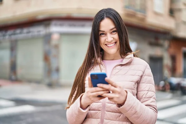 若い女性は路上でスマートフォンを使って自信を持って笑顔 — ストック写真