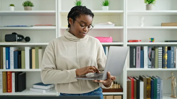 アフリカ系アメリカ人の女子学生が図書館大学のノートパソコンを使って — ストック写真