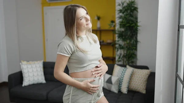 Jonge Zwangere Vrouw Glimlachen Zelfverzekerd Aanraken Buik Thuis — Stockfoto