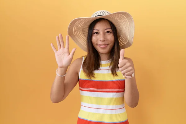 中世中国の女性身に着けています夏の帽子以上黄色の背景ショーと指摘指番号6ながら笑顔自信と幸せ — ストック写真