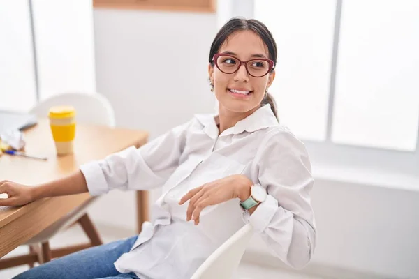 若い美しいですヒスパニック女性ビジネスワーカー笑顔自信に満ちた上のテーブルに座ってオフィス — ストック写真