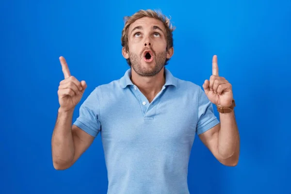 Hombre Caucásico Pie Sobre Fondo Azul Asombrado Sorprendido Mirando Hacia —  Fotos de Stock